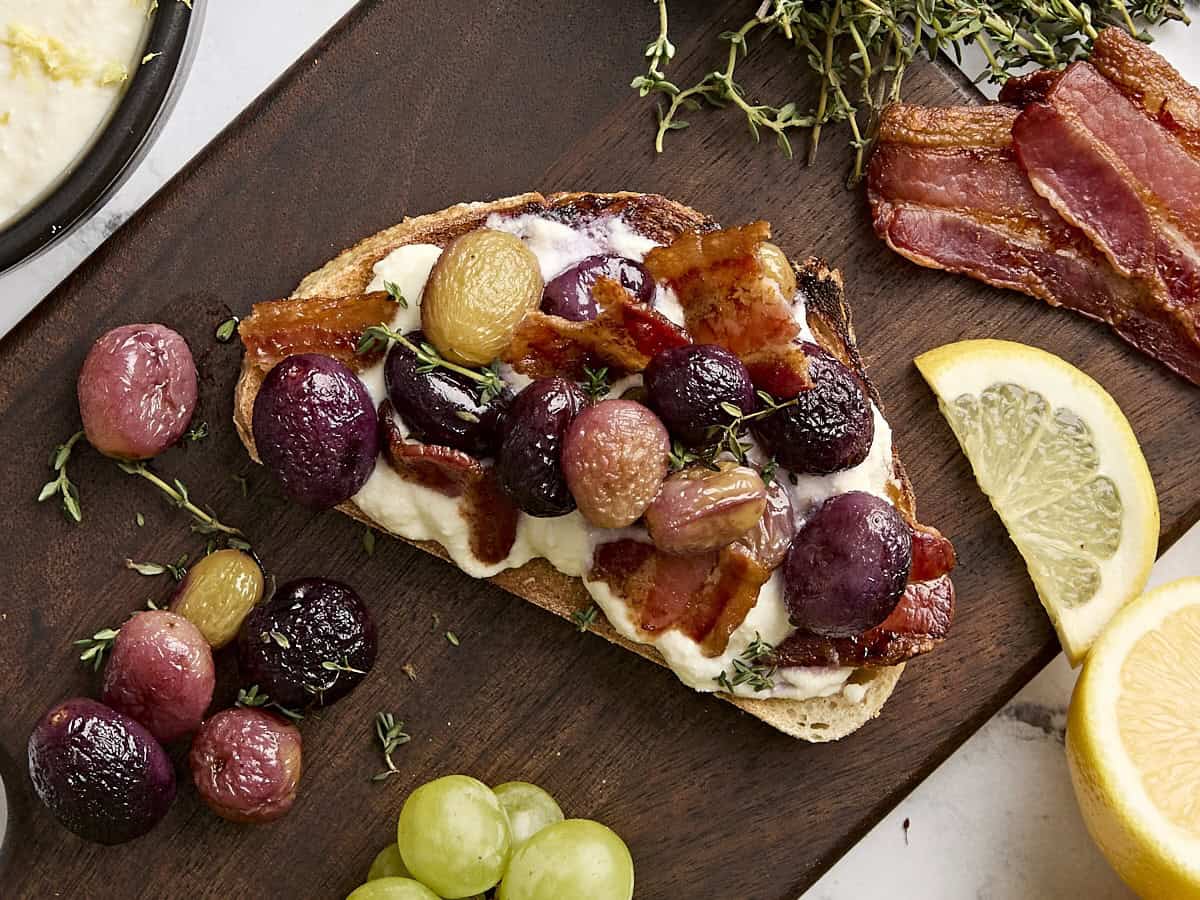 Vue aérienne du pain grillé à la ricotta avec raisins rôtis, thym et bacon.