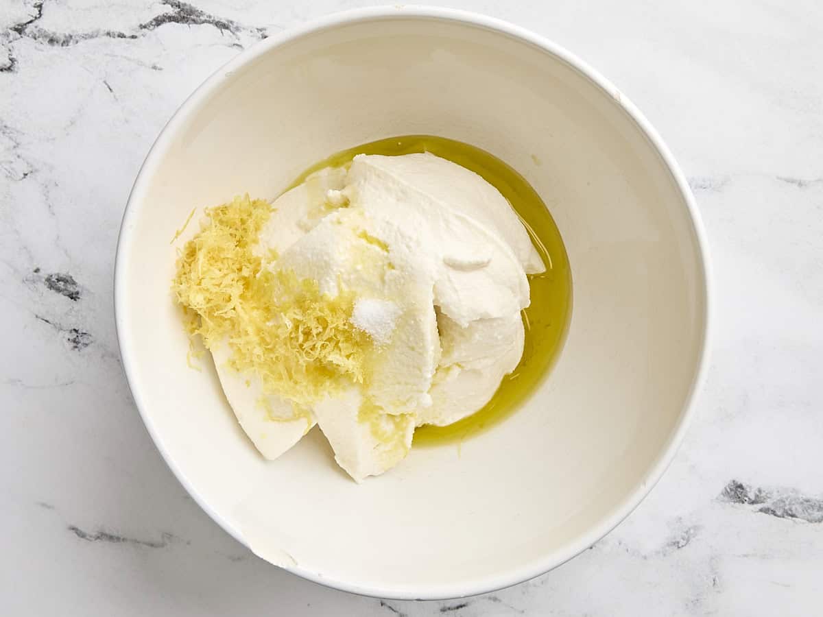 Ricotta, huile d'olive et zeste de citron dans un bol à mélanger.