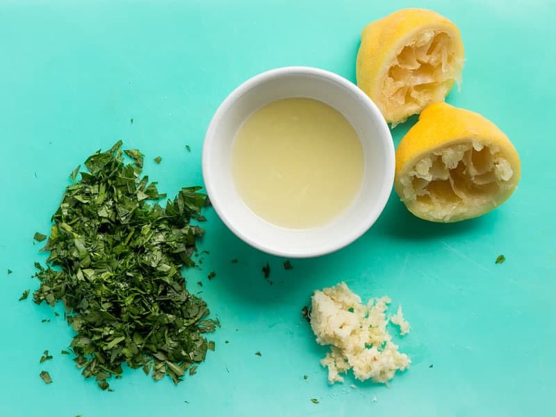 Vue aérienne du jus de citron, du persil haché et de l'ail émincé.