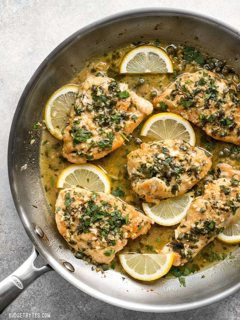 Poêle pleine de poulet piccata citronné, saumâtre, beurré et aillé.