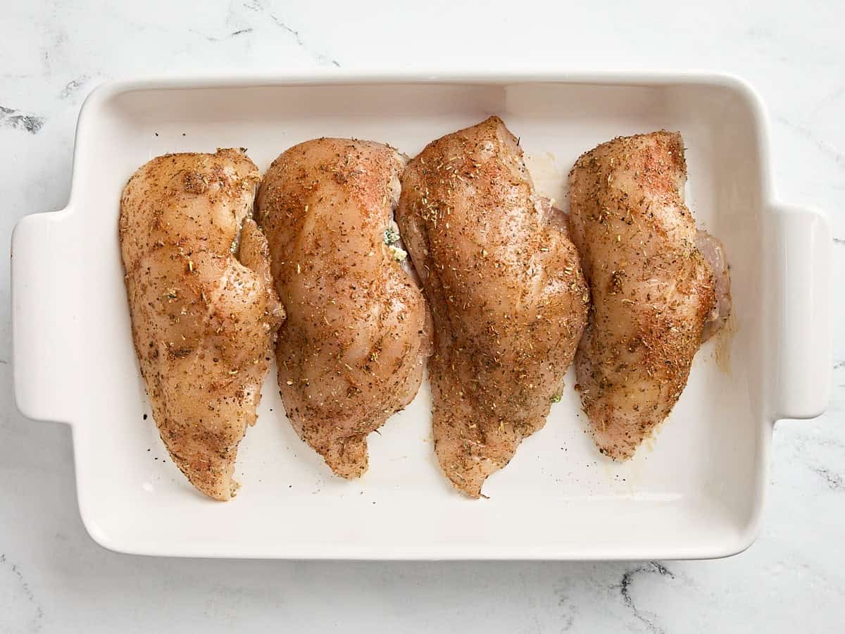 Poitrines de poulet farcies aux épinards dans un plat allant au four, prêtes à passer au four.
