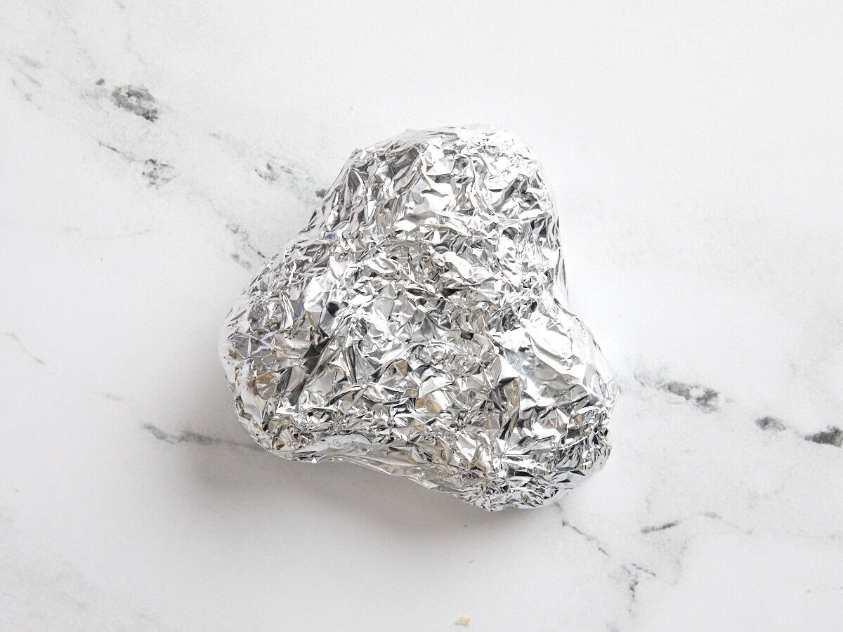 Trois têtes d'ail enveloppées dans du papier d'aluminium.