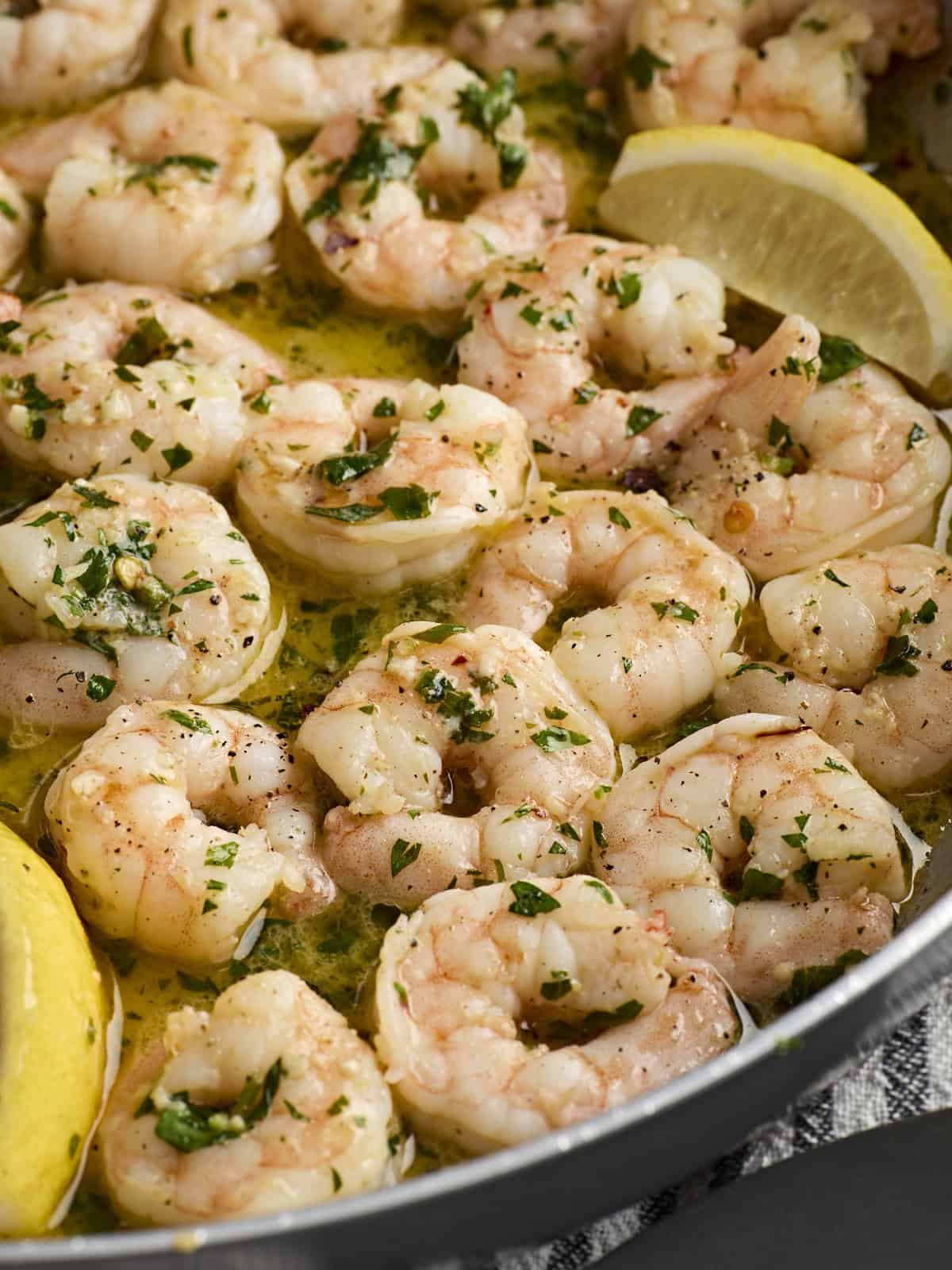 Gros plan de langoustines aux crevettes dans une poêle avec des quartiers de citron.