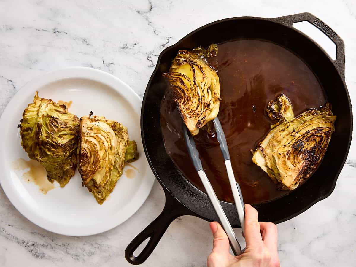 Patires de cuisine en retirant des steaks de chou d'une poêle en fonte à une assiette.
