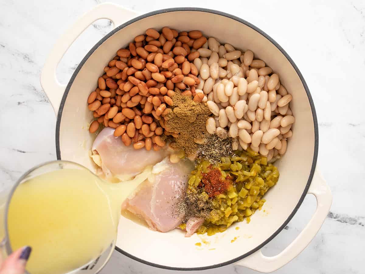 Le poulet, les haricots, les épices et le bouillon ont ajouté au pot. 