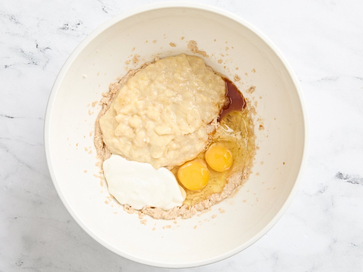 Éclaire des bananes, du yaourt, des œufs et du beurre à la crème et du sucre dans un bol.