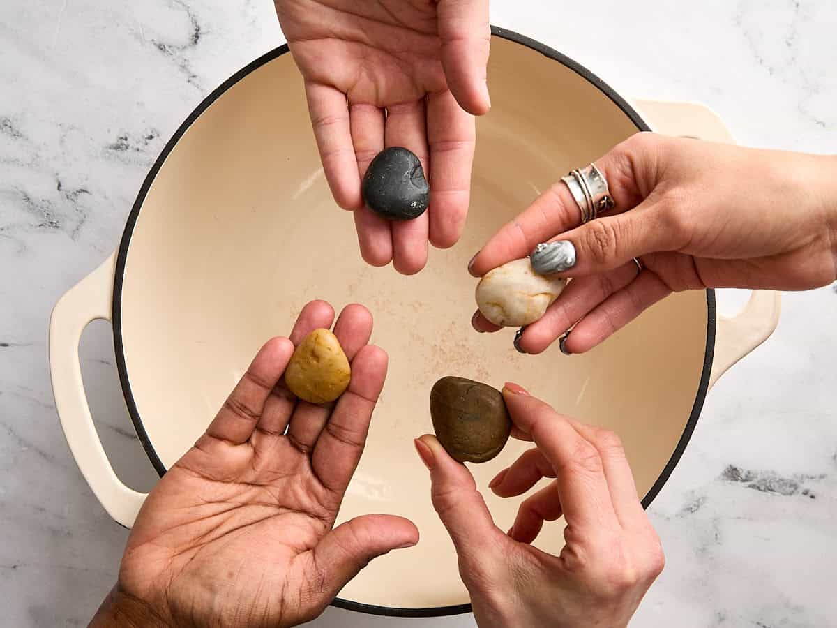 Quatre mains tenant une petite rivière sur une marmite.