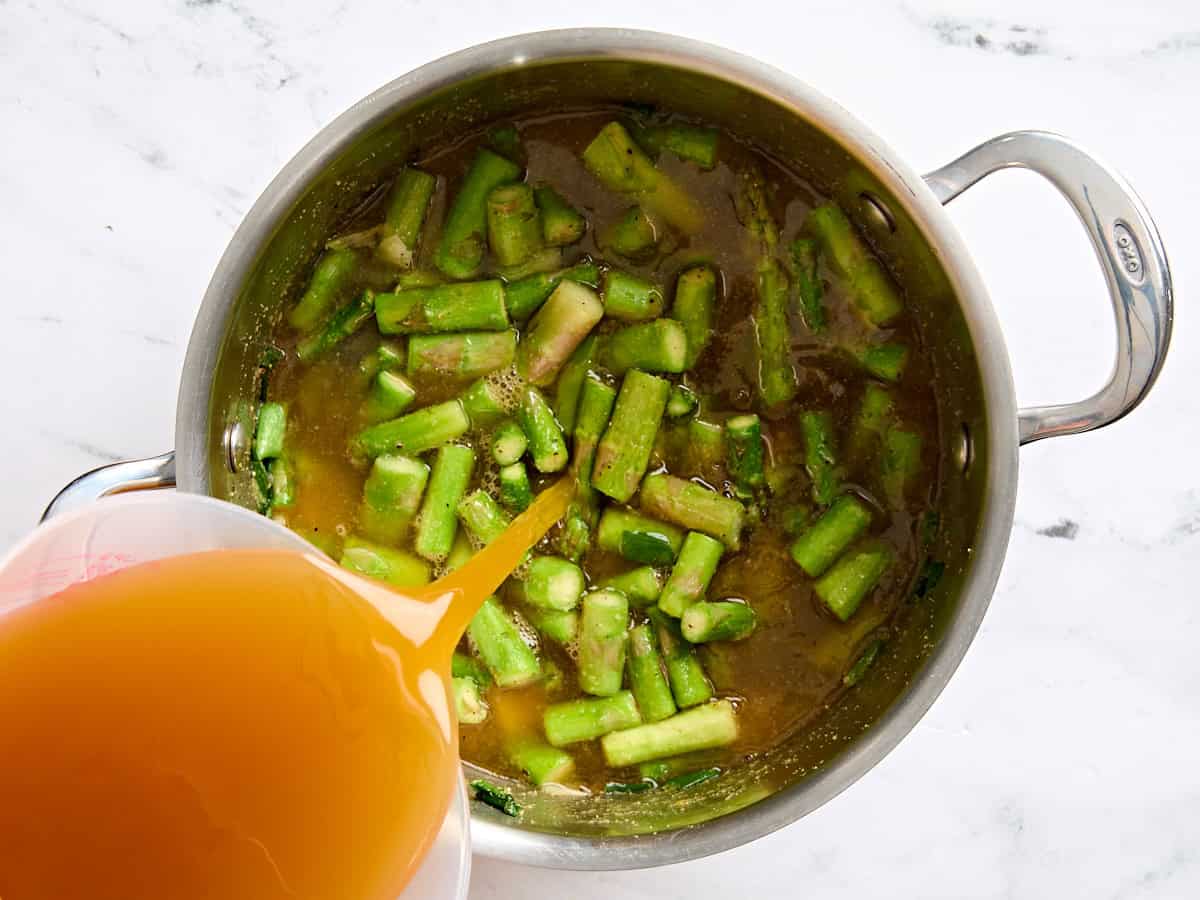 Bouillon de légumes ajouté aux asperges sautées dans une sauce.