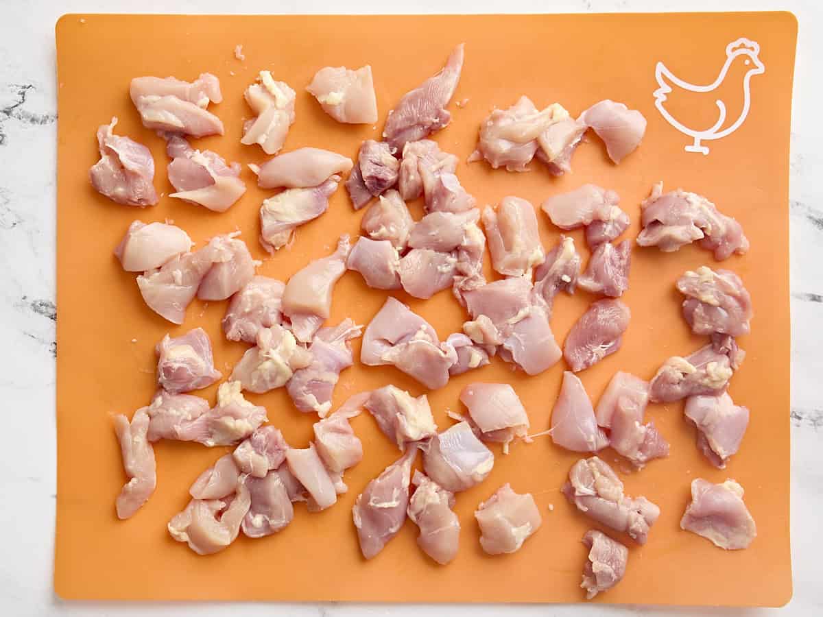 Cuisses de poulet en dés sur un tapis de coupe.