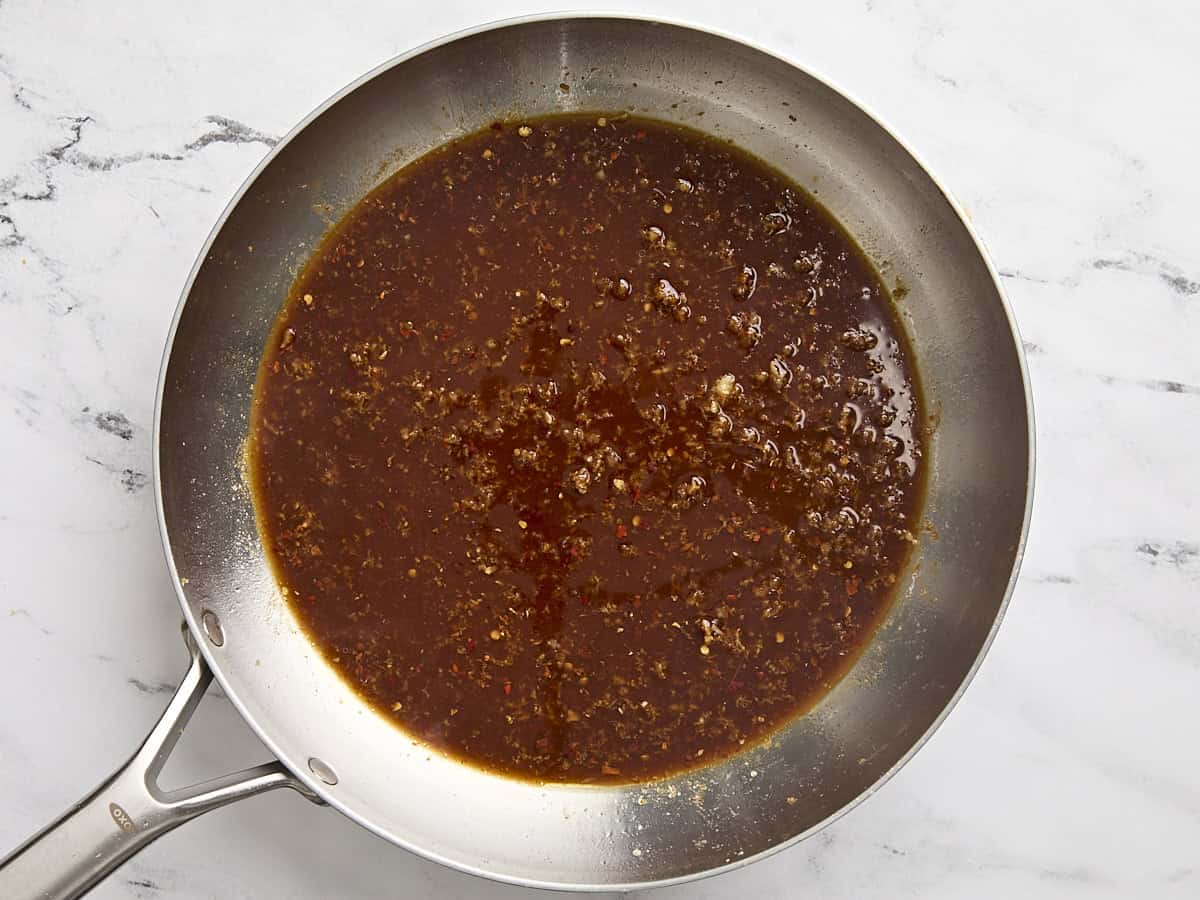 Sauce orange mijote dans une poêle.