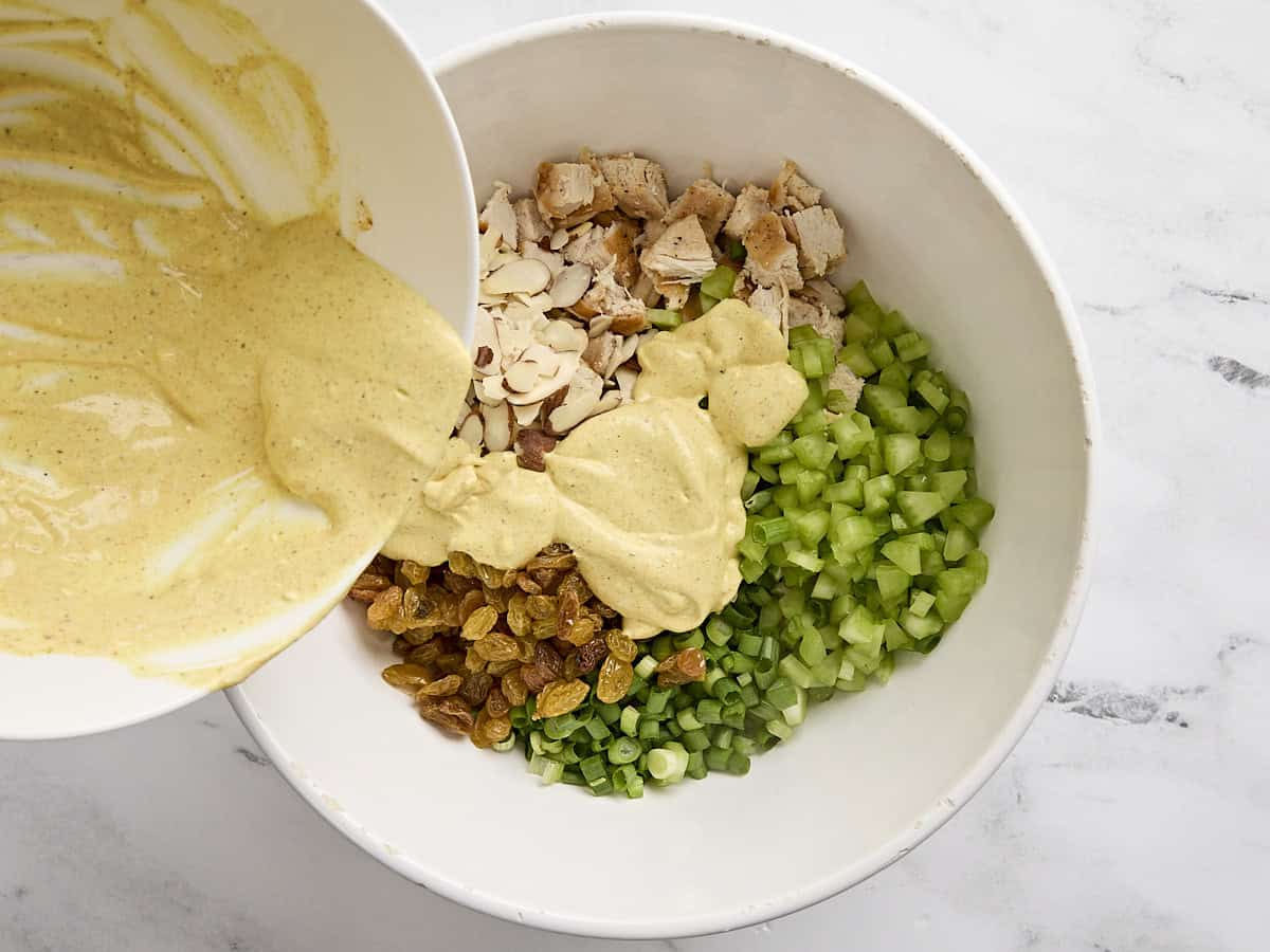 La vinaigrette versée dans les ingrédients pour la salade de curry de poulet.