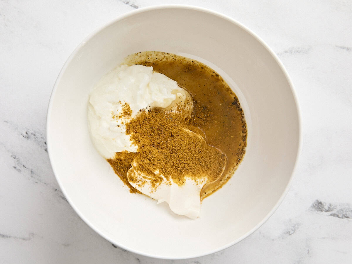 Yaourt, mayonnaise, assaisonnements et poudre de curry dans un bol à mélanger.
