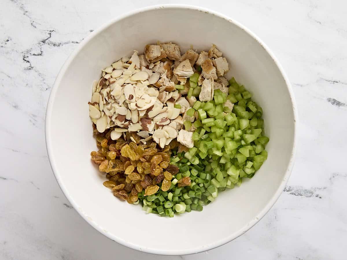 Poulet cuit en dés, céleri, haricots verts et raisins secs dans un bol à mélanger.