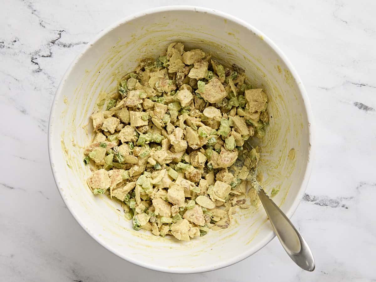 Un bol de salade de poulet au curry maison avec une cuillère.