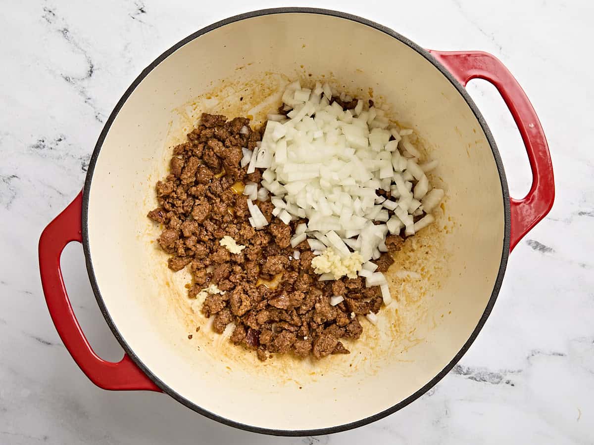 L'ail haché et l'oignon coupés en dés ajoutés au pot de chorizo ​​cuit.