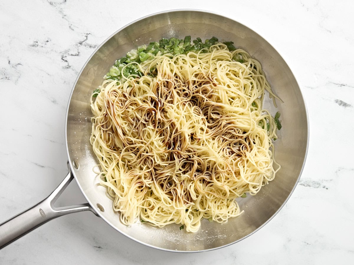 Nouilles à l'ail avec sauce ajoutée dans une poêle.