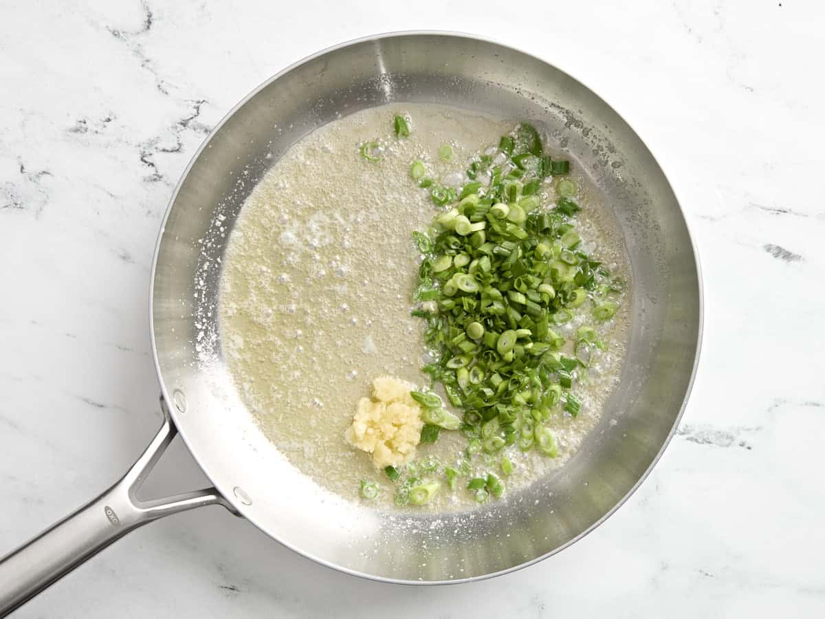 Beurre fondu dans une poêle avec des oignons verts en tranches et de l'ail haché.