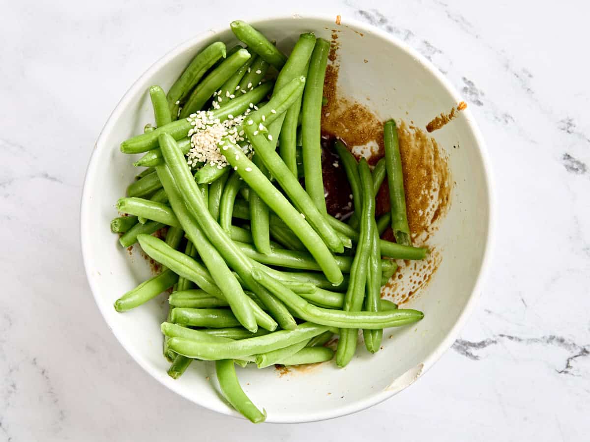 Les haricots verts ajoutés au bol de glaçage à l'huile de sésame.