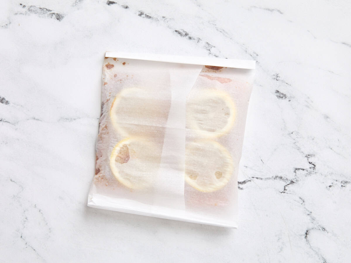 Des filets de saumon glacés enveloppés dans une parcelle en papier parchemin pour la cuisson.