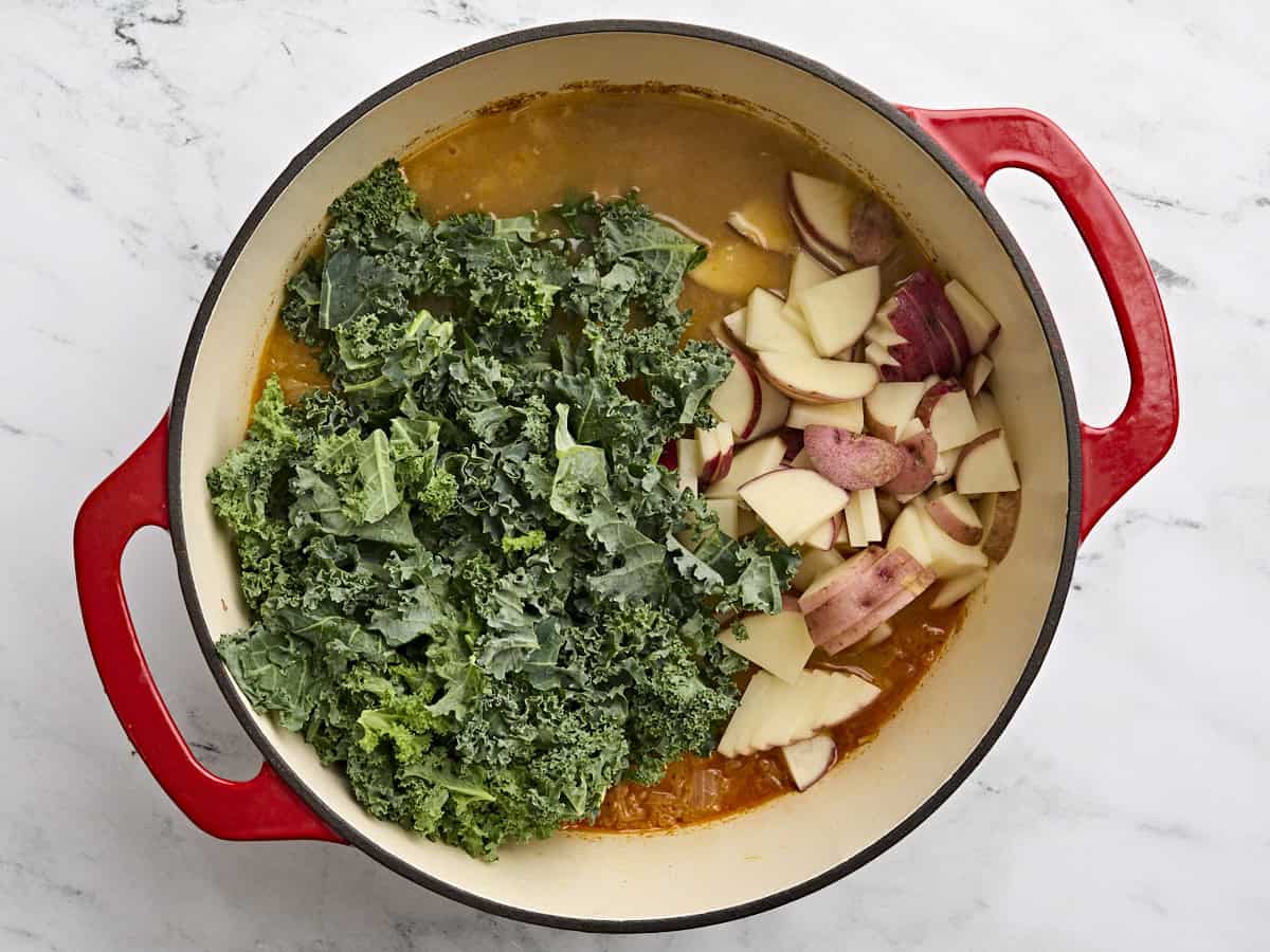 Les pommes de terre en tranches et le chou frisé ont ajouté à un pot de Zuppa Toscana.