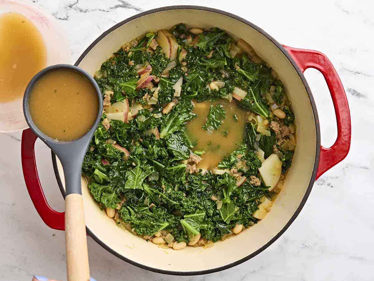 Une louche retirant du bouillon d'un pot de Zuppa Toscana.