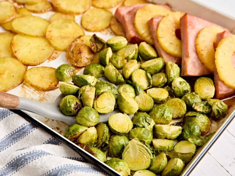 Side view of a spatula taking some Brussels sprouts from a sheet pan Easter dinner.