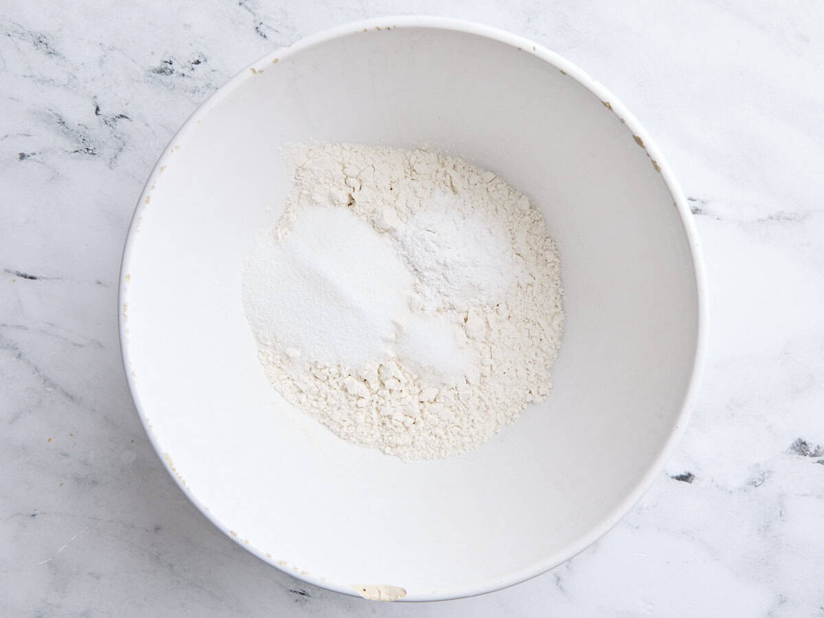 Farine, levure chimique, sucre. et le sel dans un bol à mélanger blanc.