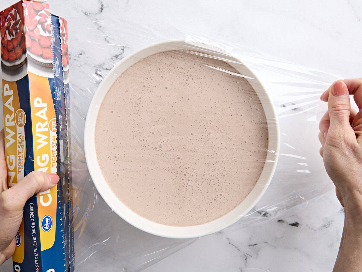 Le mélange liquide pour un gel fait maison dans un bol recouvert de pellicule plastique.
