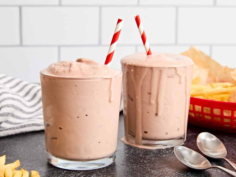 Side view of two homemade frostys in a glass with a straw.