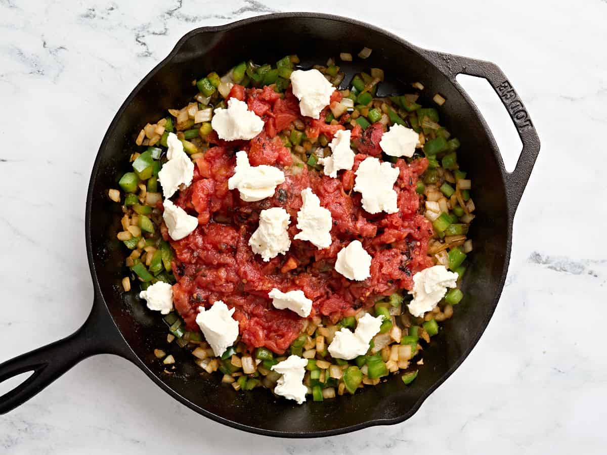 Le fromage à la crème et les tomates en dés ajoutées aux oignons sautés et au poivron vert.