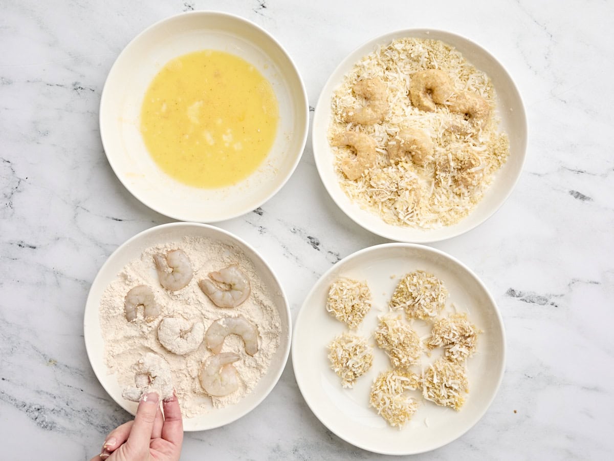 Les crevettes étant draguées dans un lavage d'oeufs, puis la noix de coco et le panier de panko, puis la farine.