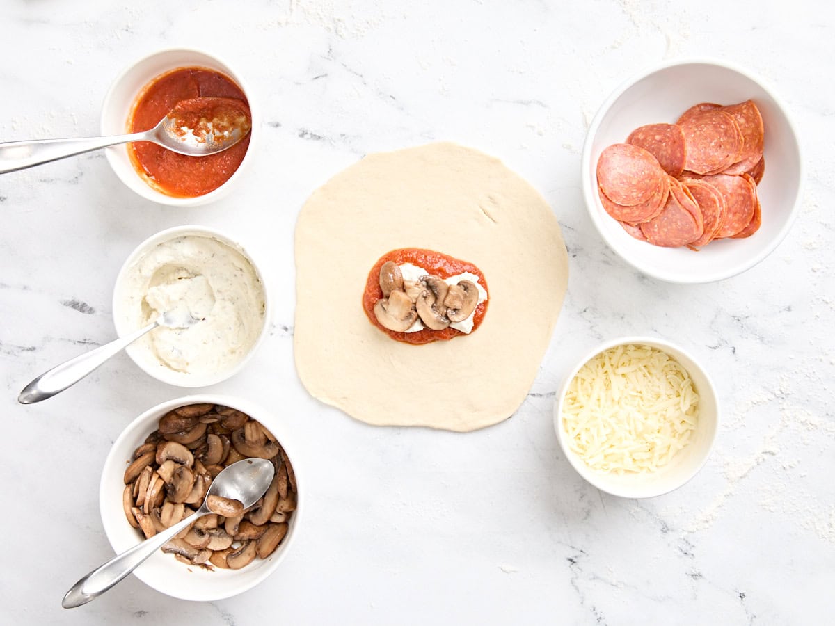 Un cercle de pâte à pizza étant garni de garnitures