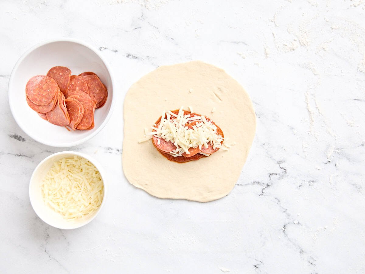 Le pepperoni et le fromage ajoutés à la garniture de la calzone.