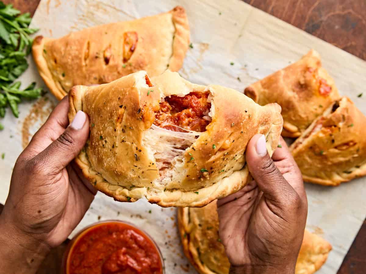 Les mains s'ouvrent une calzone de pepperoni maison.
