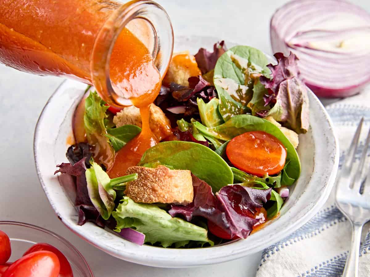 Une vinaigrette française maison versée sur un bol de salade.