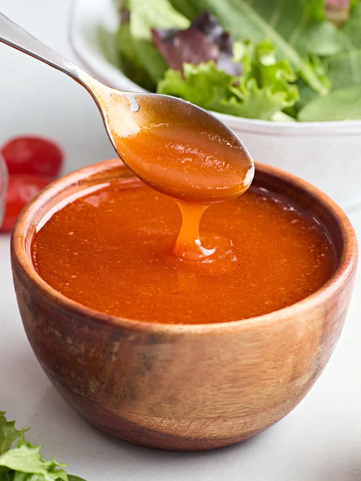 Vue latérale d'un bol de vinaigrette française, avec une cuillère en prenant.