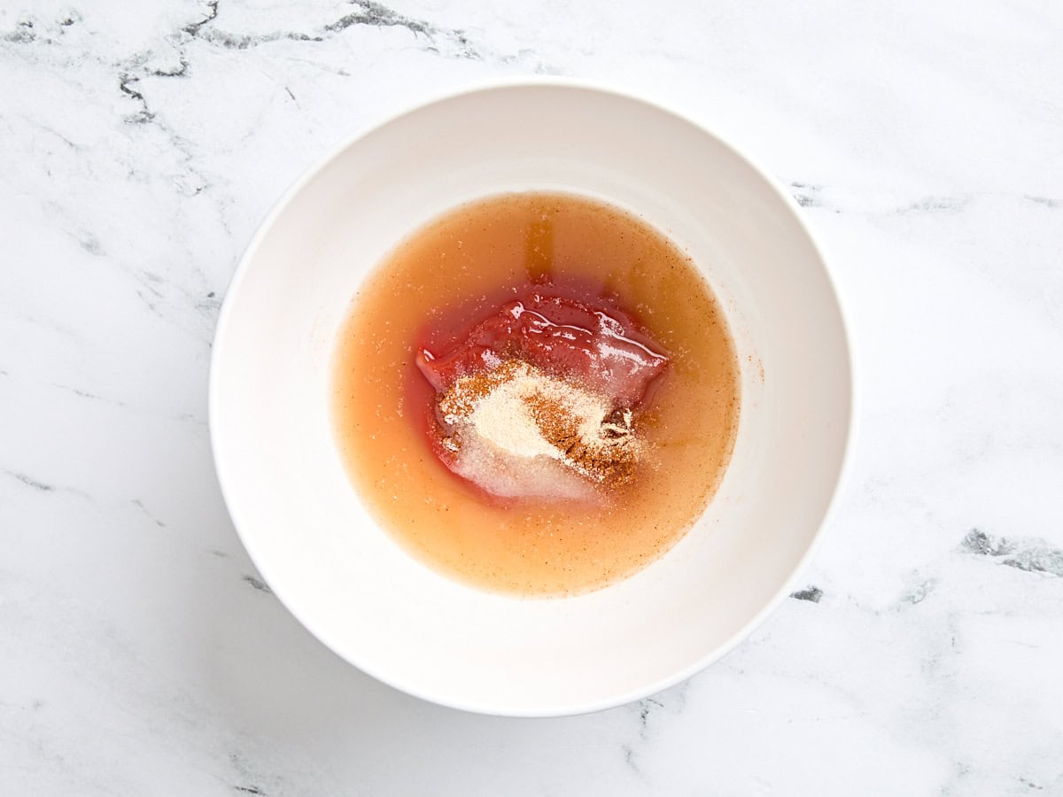 Ketchup, vinaigre, sucre, paprika, poudre d'ail, poudre d'oignon et sel dans un bol.