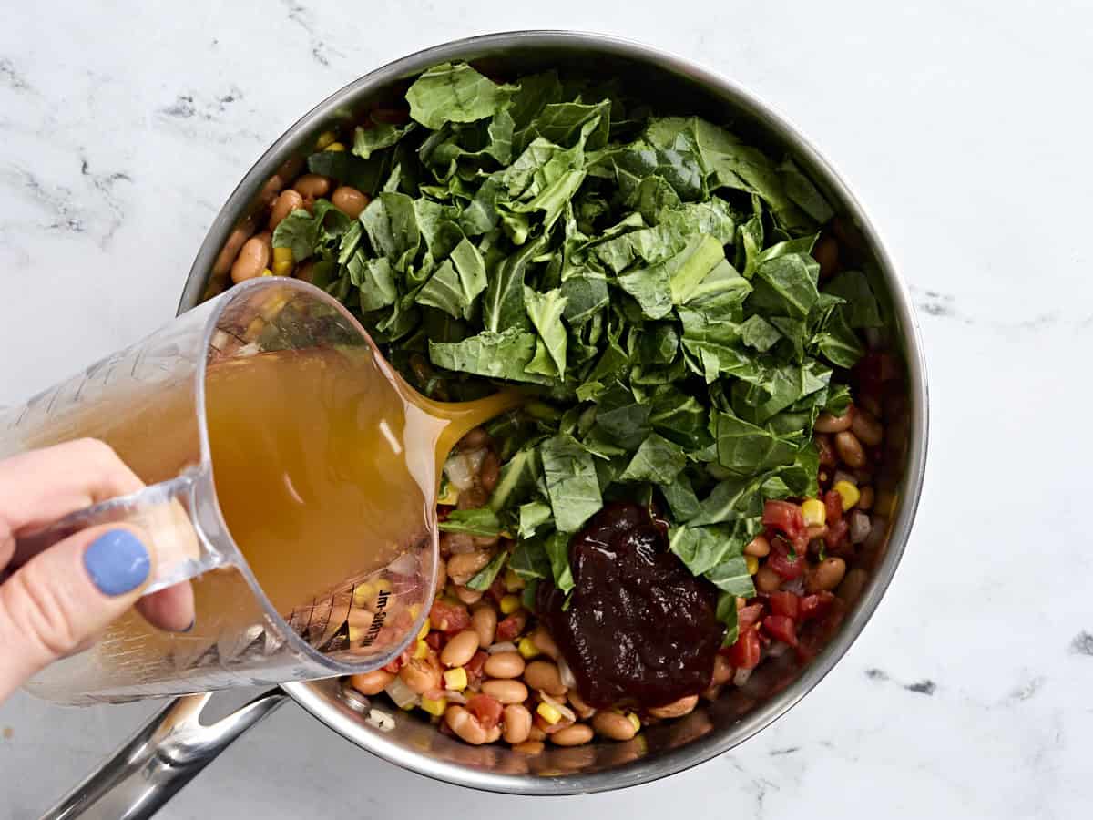 Les légumes verts du sud, la sauce barbecue et le bouillon ont ajouté à une poêle pour fabriquer des verts et des haricots.