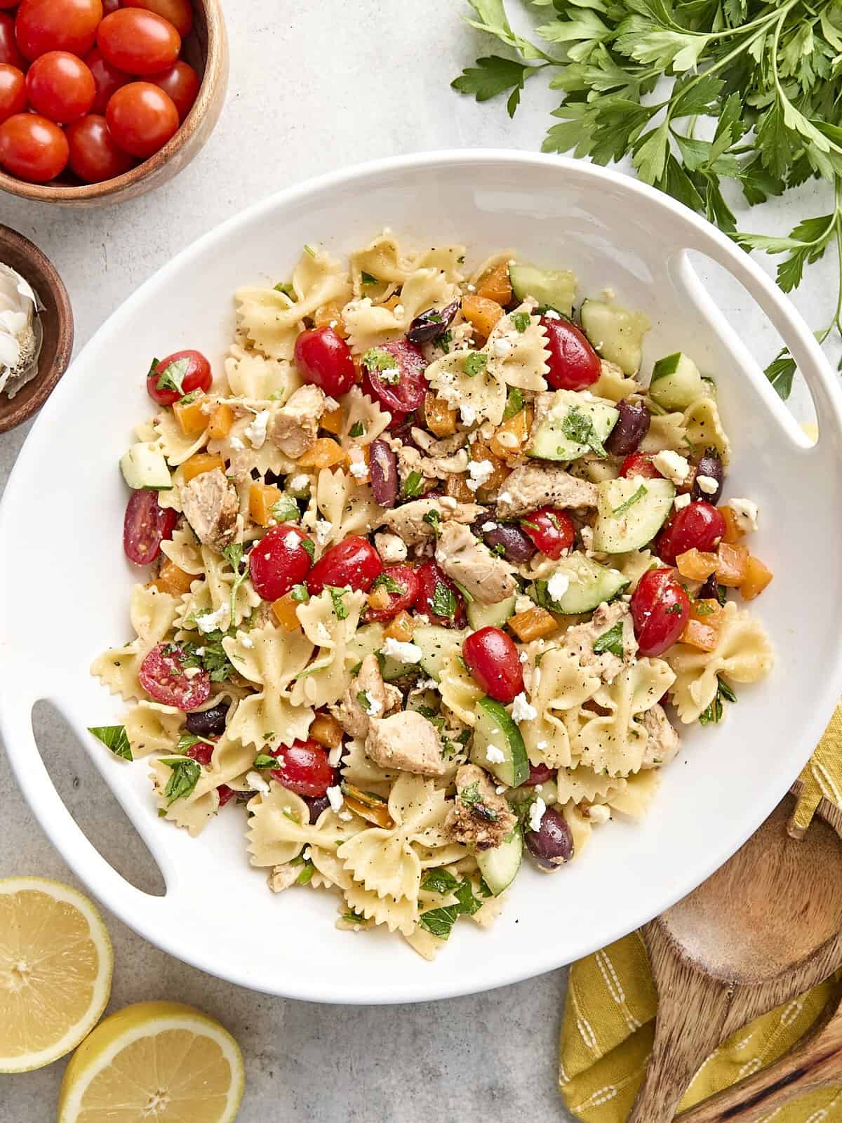 La salade de pâtes au poulet grec est le repas d'été parfaitement rafraîchissant et copieux avec son mélange de légumes et la vinaigrette à l'ail de citron acidulé. Budgetbytes.com Vue aérienne d'une salade de pâtes à poulet grec maison sur un plateau.