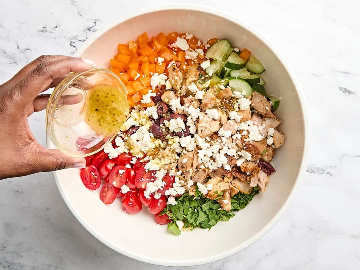 Le fromage feta ajouté aux ingrédients de la salade de poulet grec, la marinade de citron restante versée sur le dessus.