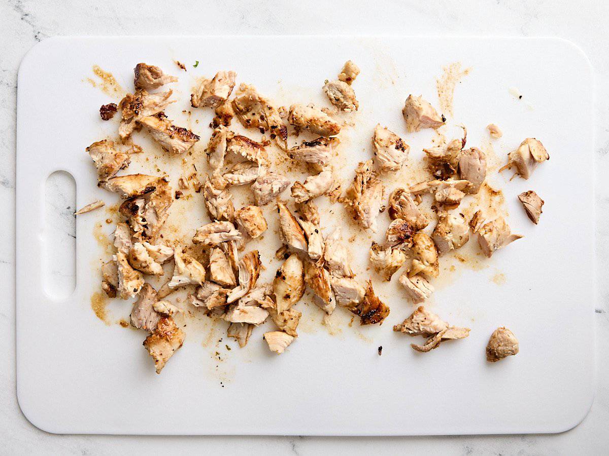 Cuisses de poulet cuites en dés sur une planche à découper.