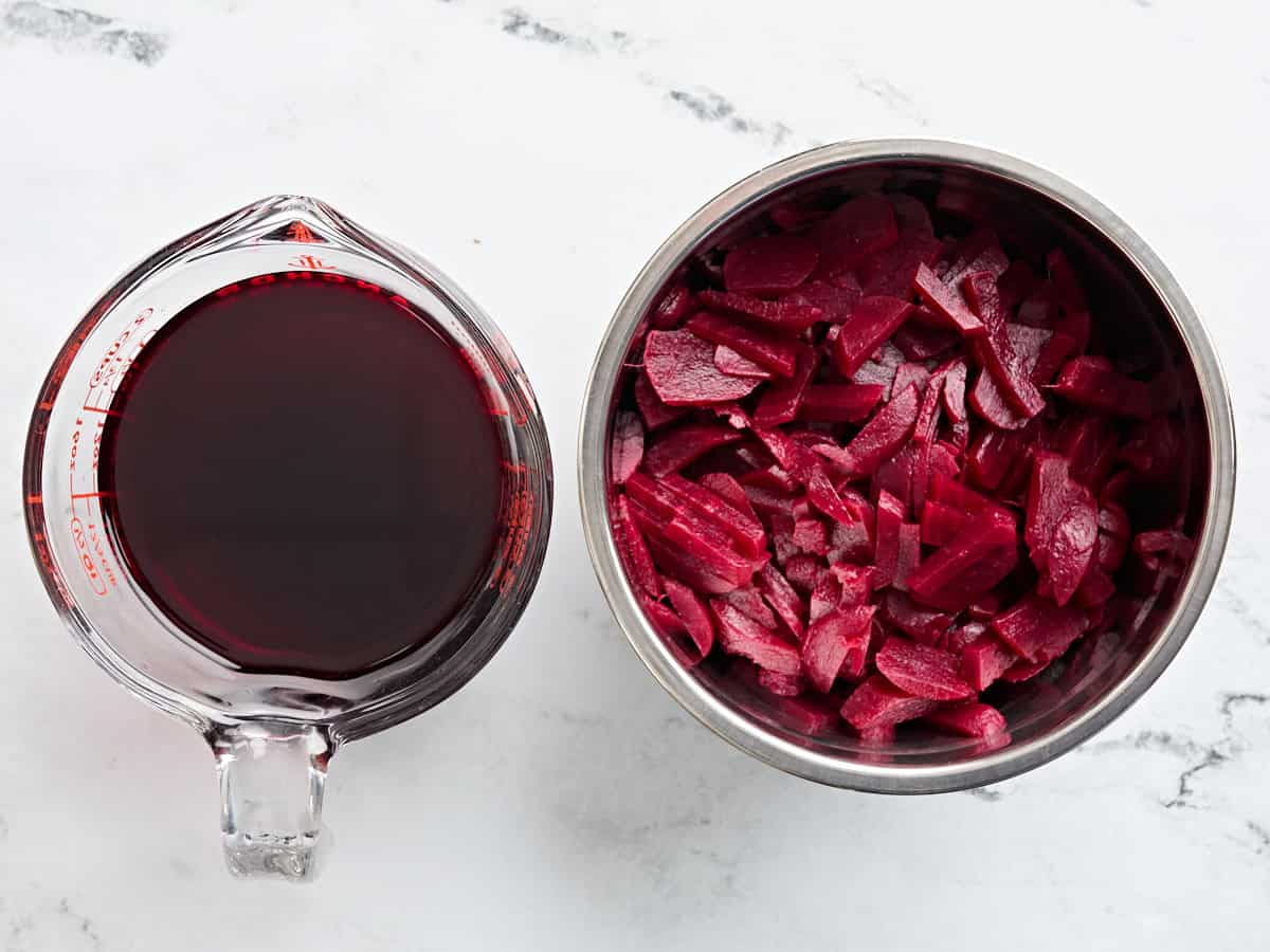 Beets en conserve dans une casserole avec le jus de la boîte dans une deuxième cruche.