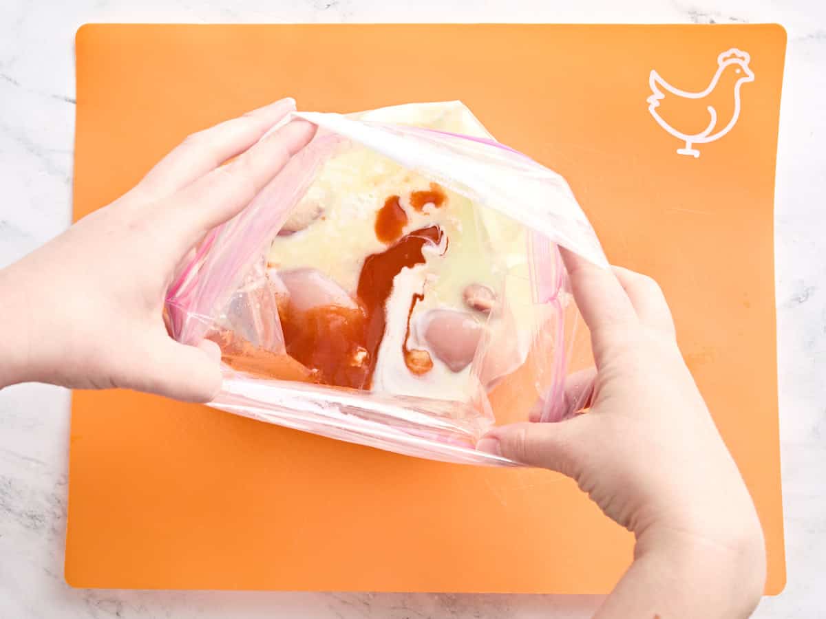 Babeurre, sauce piquante, saumure de cornichon et cuisses de poulet dans un sac en plastique.