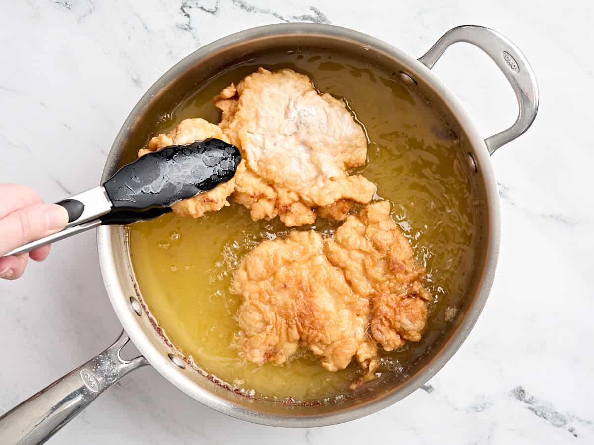 Frêtre de poulet pané dans de l'huile chaude dans une poêle.