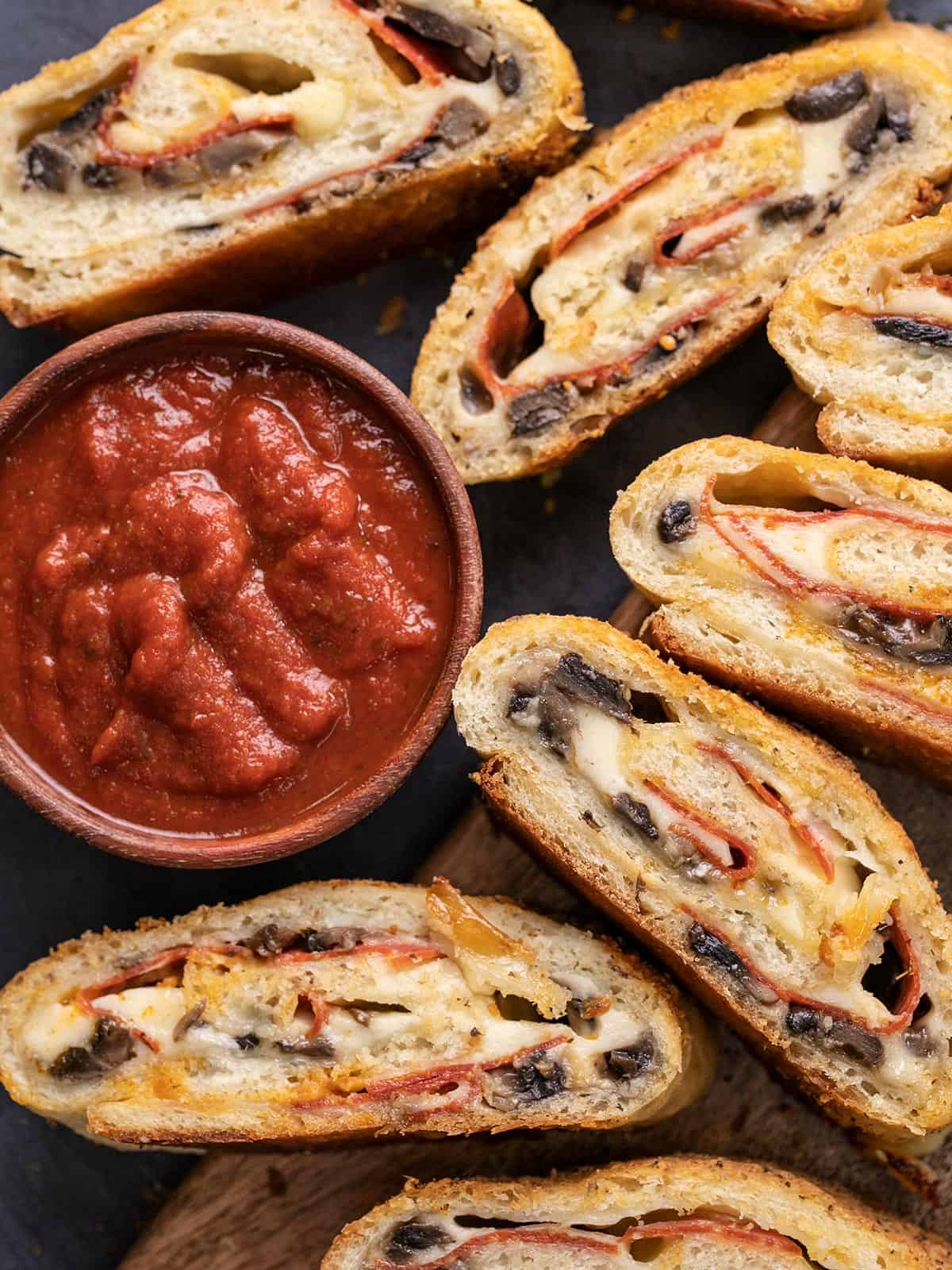 Vue aérienne des tranches de stromboli à côté d'un bol de sauce à pizza.