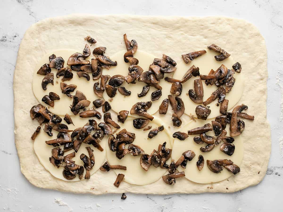 Provolone et champignons sur pâte à pizza.