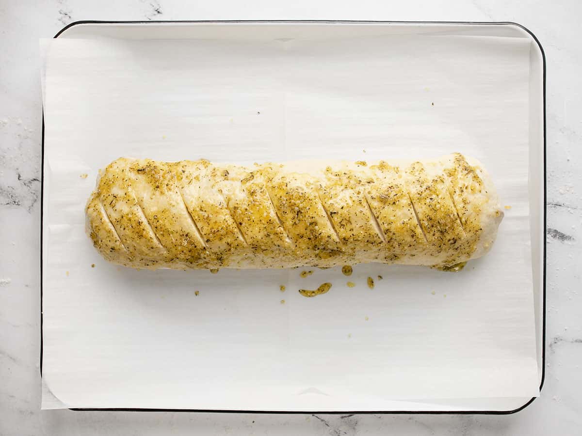 Stromboli sur une plaque à pâtisserie assaisonnée et tranchée.