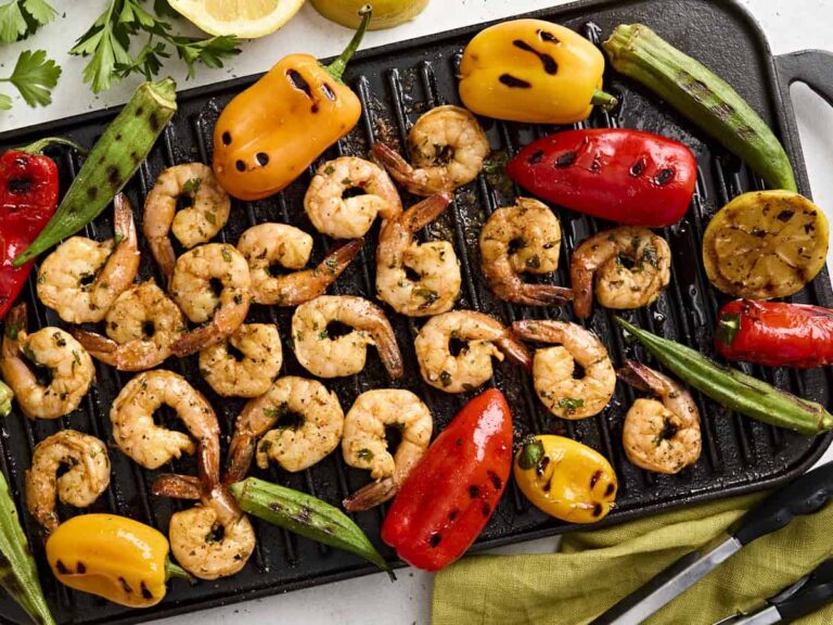 Overhead view of grilled shrimp on a grill with grilled vegetables.