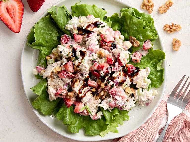 Overhead view of a strawberry chicken salad on a bed of greens.