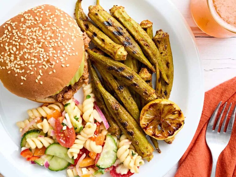 Grilled okra on a plate with a burger and pasta salad.